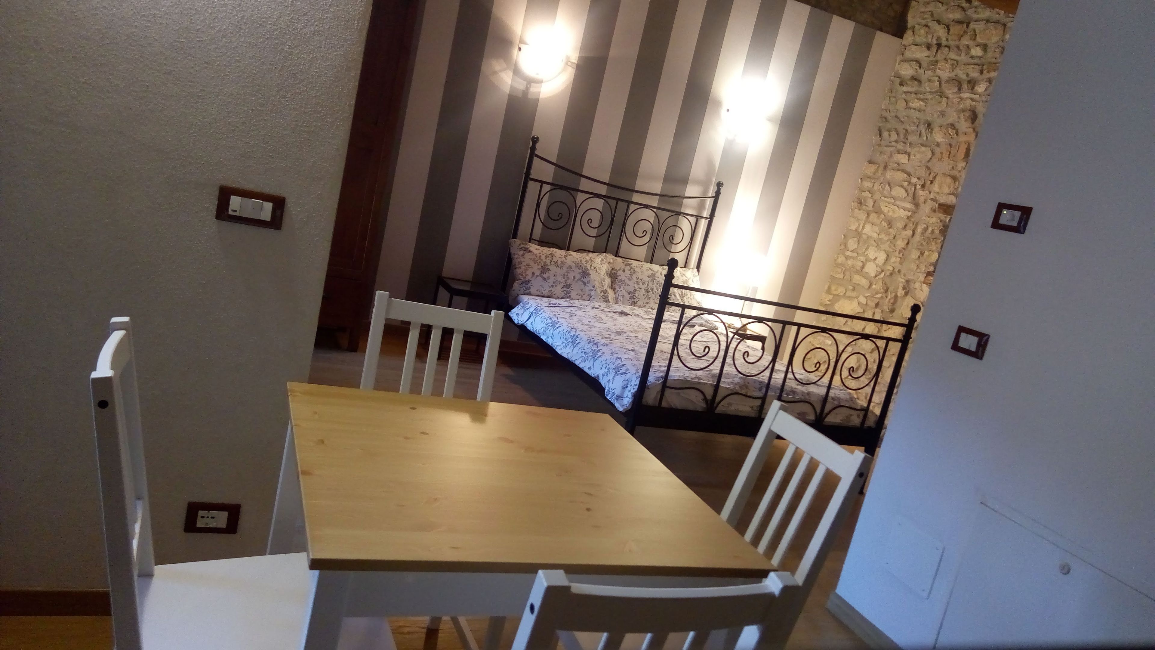 Ein Zimmer mit einem Bett, einem Holztisch und zwei weißen Stühlen.