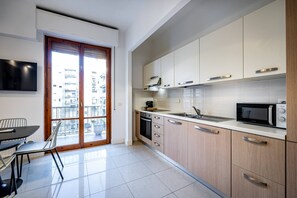 Una cuina moderna amb un finestral gran, una zona de menjador amb taula i cadires, i un televisor de pantalla plana fixat a la paret.