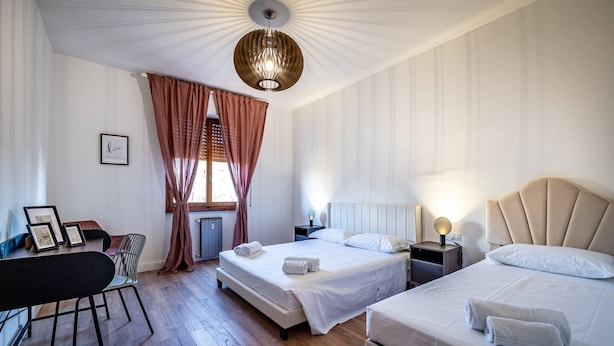 A hotel room with two beds, a desk, and a chair. - Pasquini (Florence)