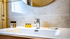A bathroom with a large mirror, a sink, and toiletries. - Pasquini (Florence)