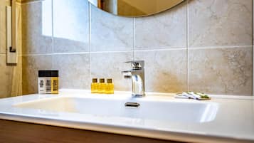 A bathroom with a large mirror, a sink, and toiletries.