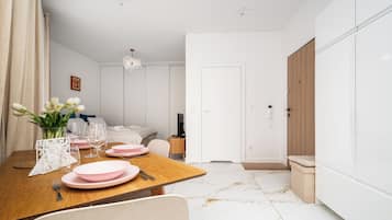 Ein modernes Hotelzimmer mit Essbereich, einem Bett, einem Kleiderschrank und einem Badezimmer.