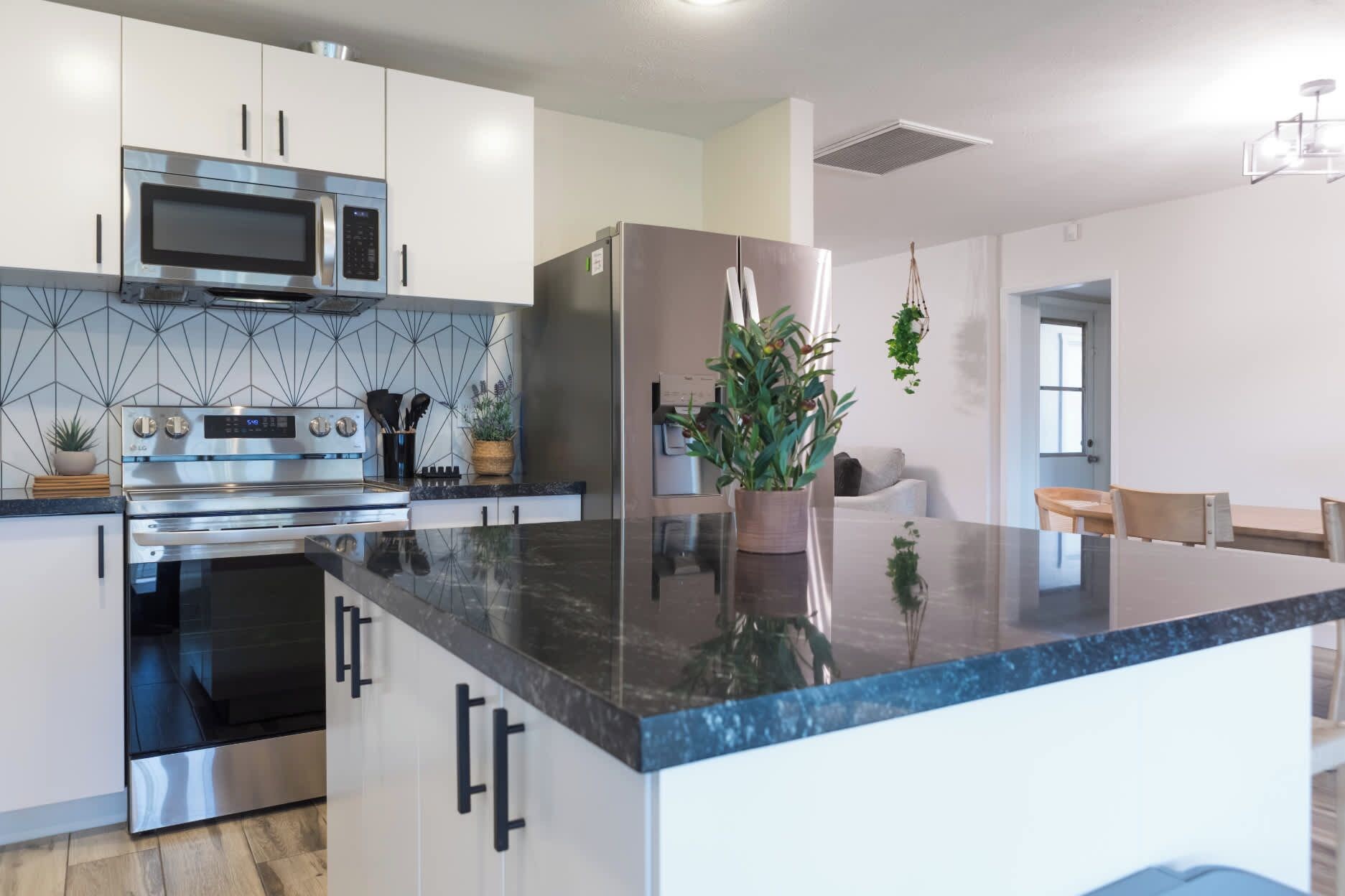 A modern kitchen with stainless steel appliances, a marble countertop, and a large island.