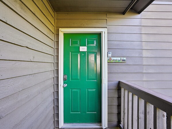 A green door with a keypad lock, a mailbox, and a wooden porch railing. - First Cub 1301 (Gatlinburg)