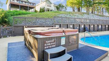 Een hottub met een waarschuwingsbord, een zwembad en een houten omheining met stoelen.