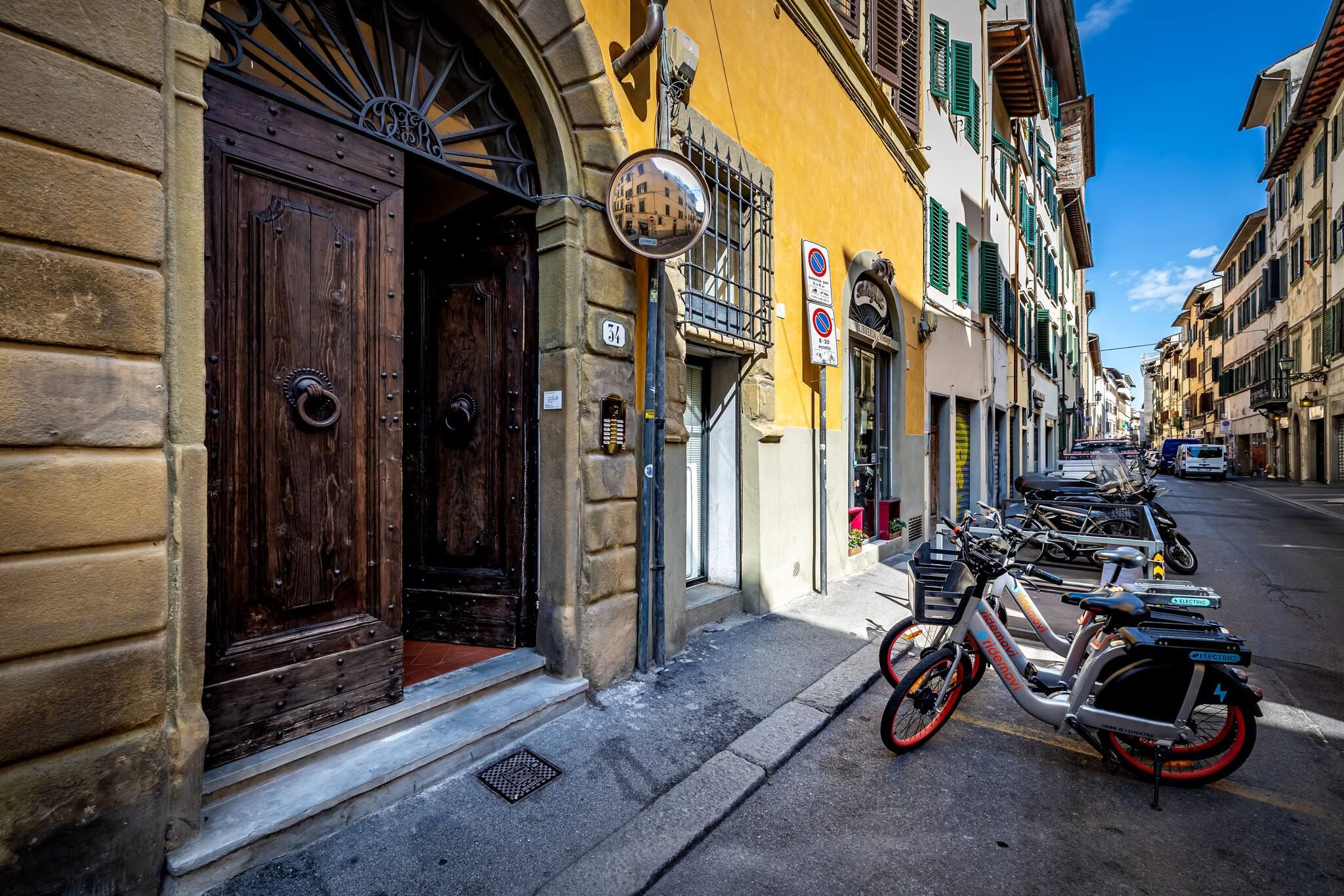 Una calle estrecha con bicicletas estacionadas, una puerta de madera y un edificio amarillo.