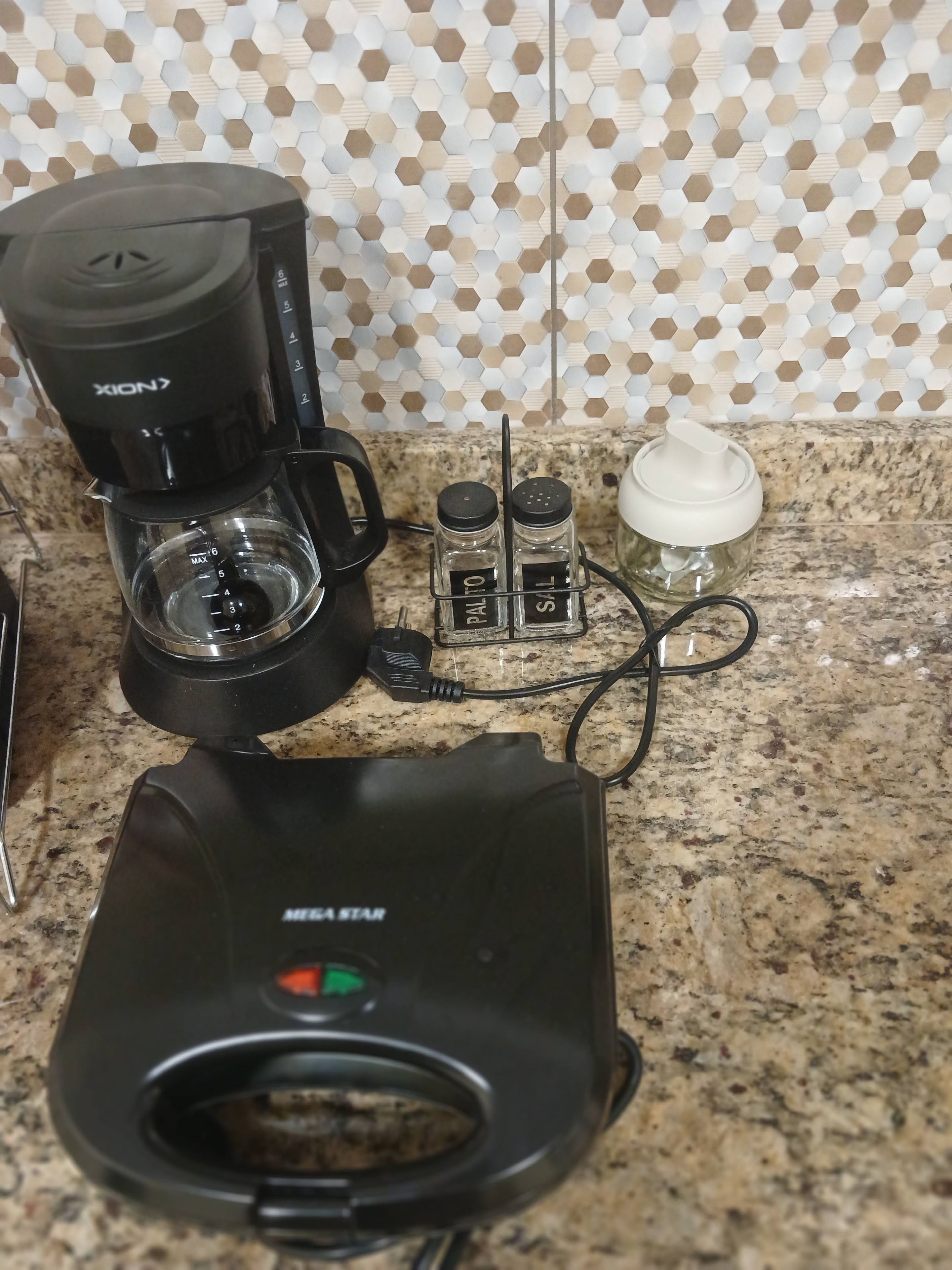 Une machine à café, des salières et des poivrières, une bouteille d’eau et une multiprise sur un plan de travail de cuisine.