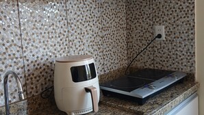 Una cocina con estufa integrada, cafetera, pileta y salpicadero decorativo.