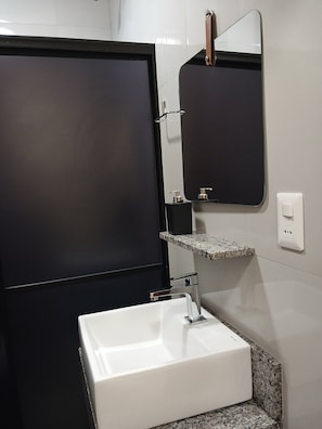 Casa de banho com lavatório branco, espelho e porta-toalhas.