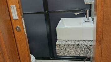 Un baño con un lavamanos blanco, pared oscura y puerta de madera.