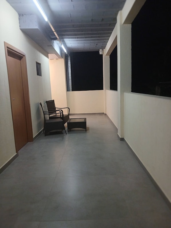 Un balcón con una silla, una mesa pequeña, una puerta y una ventana.