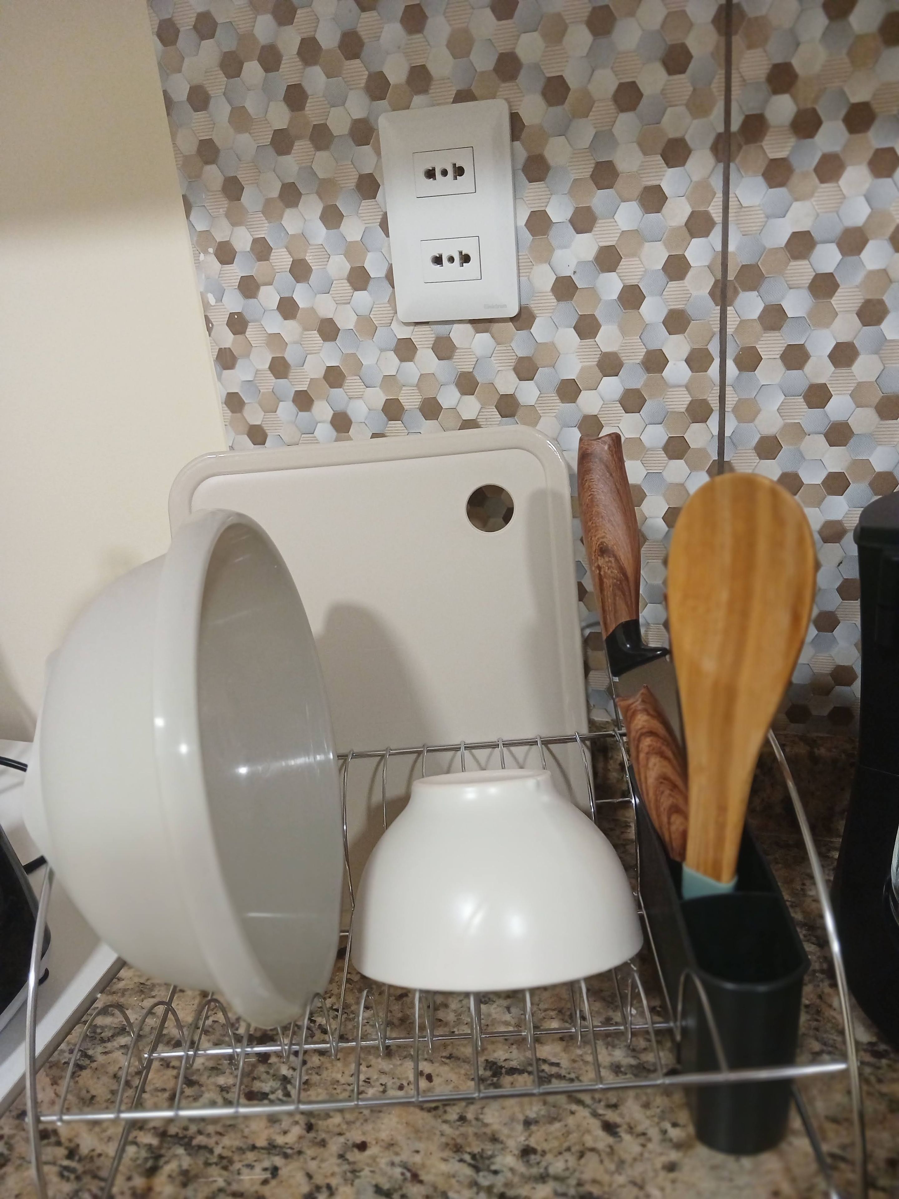 Un escurridor de utensilios de cocina con una olla blanca y una cuchara de madera.