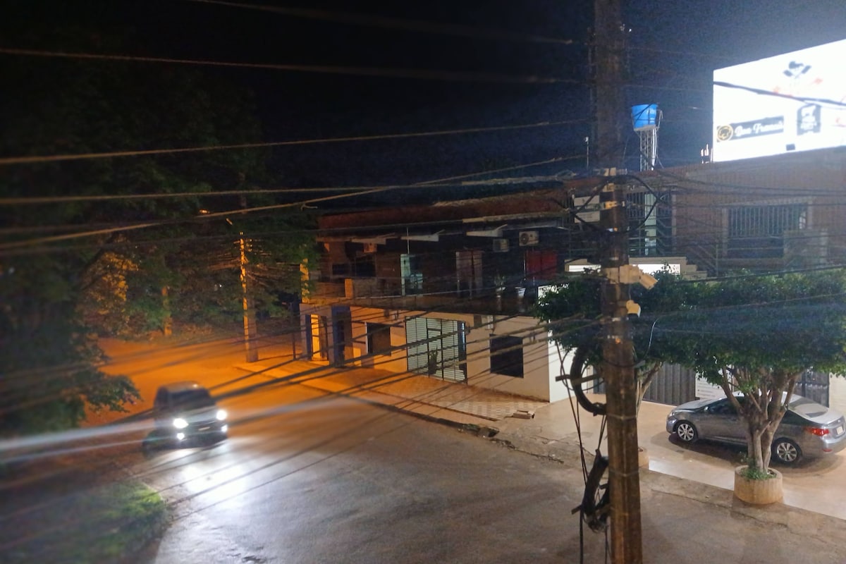 A nighttime street view with a building, a billboard, and parked cars.