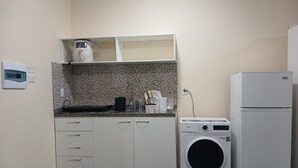 Una cocina funcional con lavadora, refrigerador y microondas.