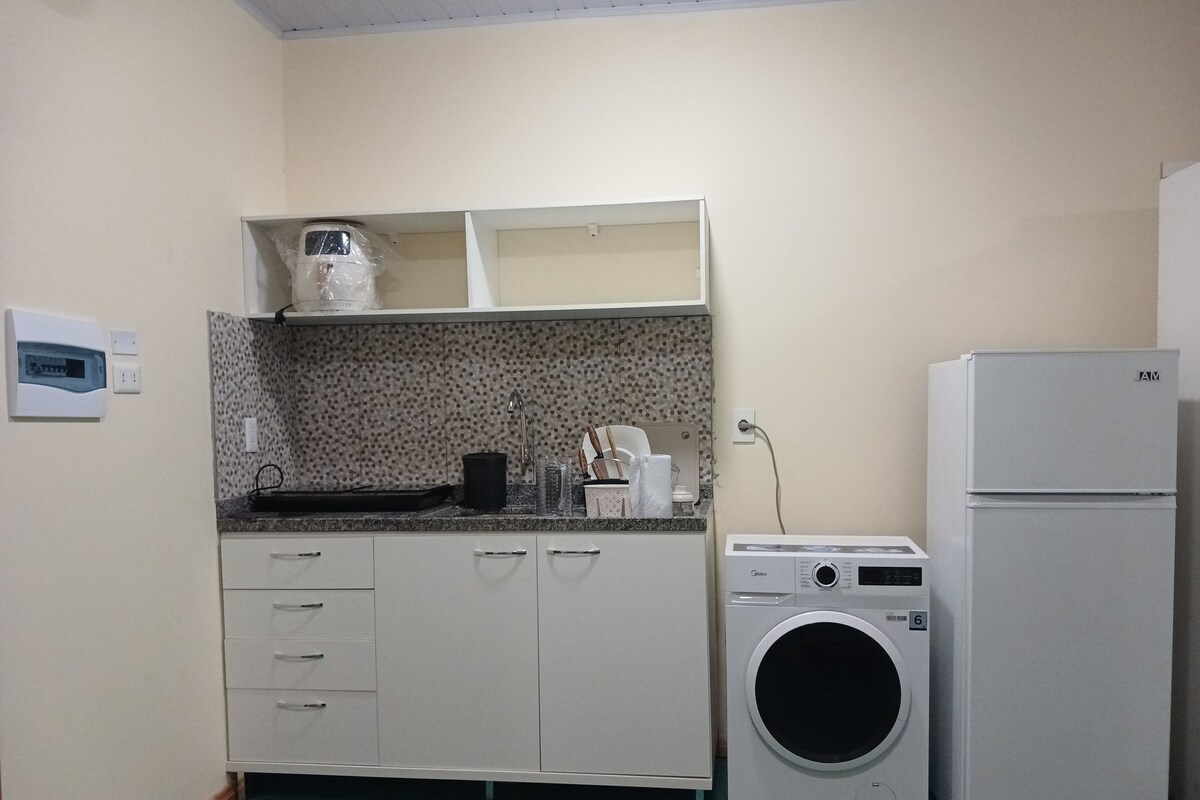 Una cocina funcional con lavadora, refrigerador y microondas.