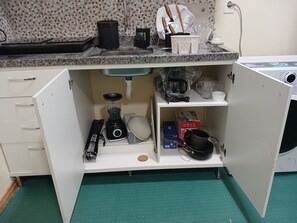 Uma cozinha com bancada de granito, máquina de lavar louça embutida e diversos eletrodomésticos.