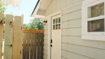 A wooden gate leading to a white building with a window and a door.