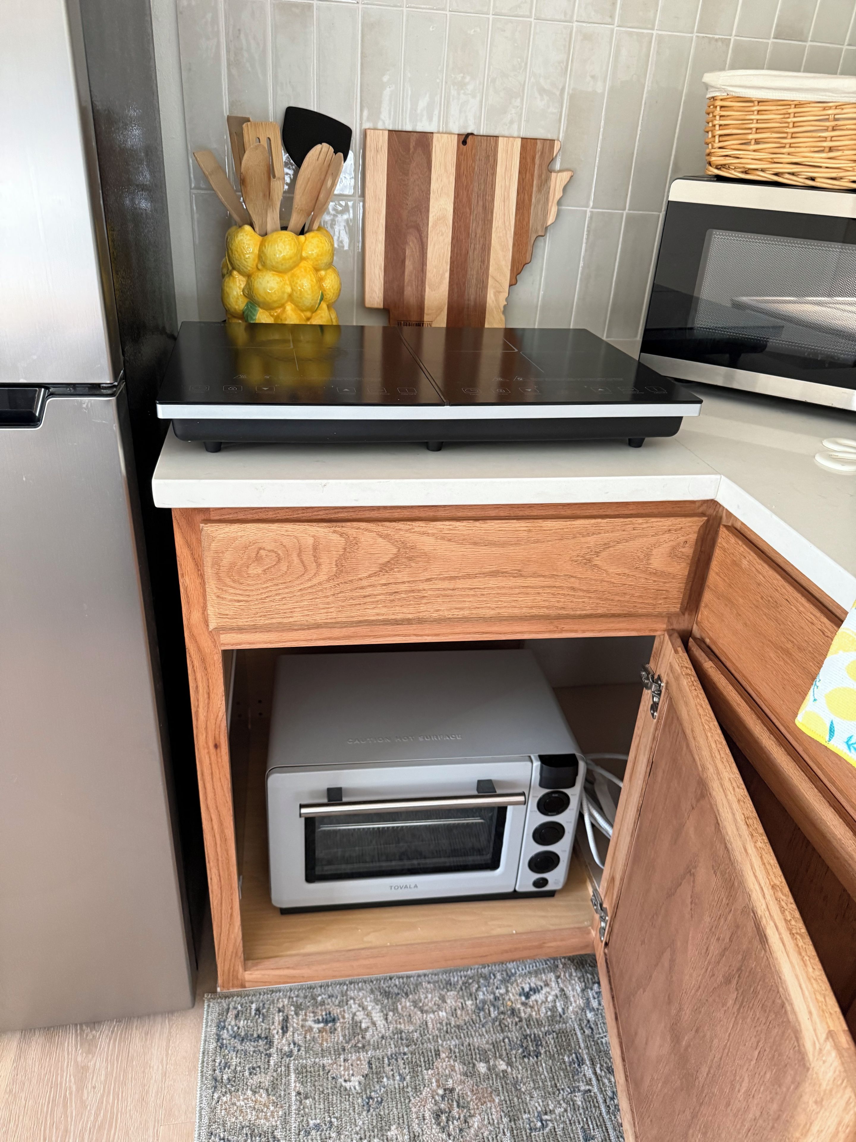 Una cocina con microondas integrado, horno tostador y un armario de madera.