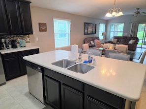 A modern kitchen with a central island, built-in appliances, and a dining area with a sofa and table.