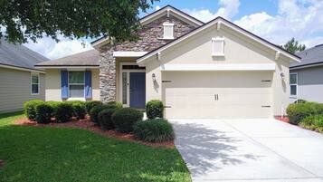 A residential house with a stone facade, a garage, and a well-maintained lawn.