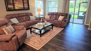 A living room with two brown sofas, a glass coffee table, and a patterned rug. - Modern Open Concept 3/2 Retreat (Orange Park)