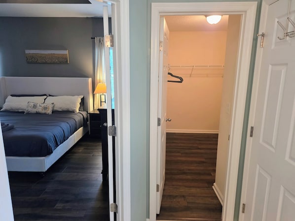 A bedroom with a bed, a nightstand, a lamp, and a wall-mounted picture.