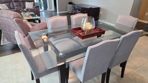 Een eetgedeelte met een glazen tafel, comfortabele stoelen en een decoratieve dienblad.