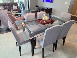 A dining area with a glass table, cushioned chairs, and a decorative tray.