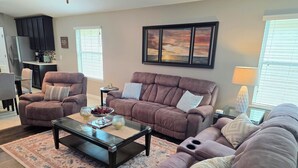 A living room with a sofa set, a coffee table, and a dining area with a table and chairs. - Modern Open Concept 3/2 Retreat (Orange Park)