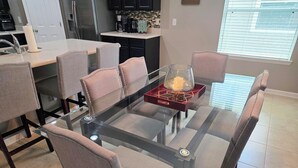 A modern dining area with a glass-top table, cushioned chairs, and a decorative centerpiece. - Modern Open Concept 3/2 Retreat (Orange Park)