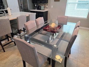Un espace repas moderne avec une table à plateau en verre, des chaises rembourrées et un élément décoratif central.