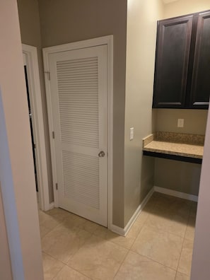 A hallway with a closed door, a countertop, and cabinets.