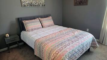Ein Schlafzimmer mit einem Bett, einem Nachttisch und zwei an der Wand befestigten Bildern.