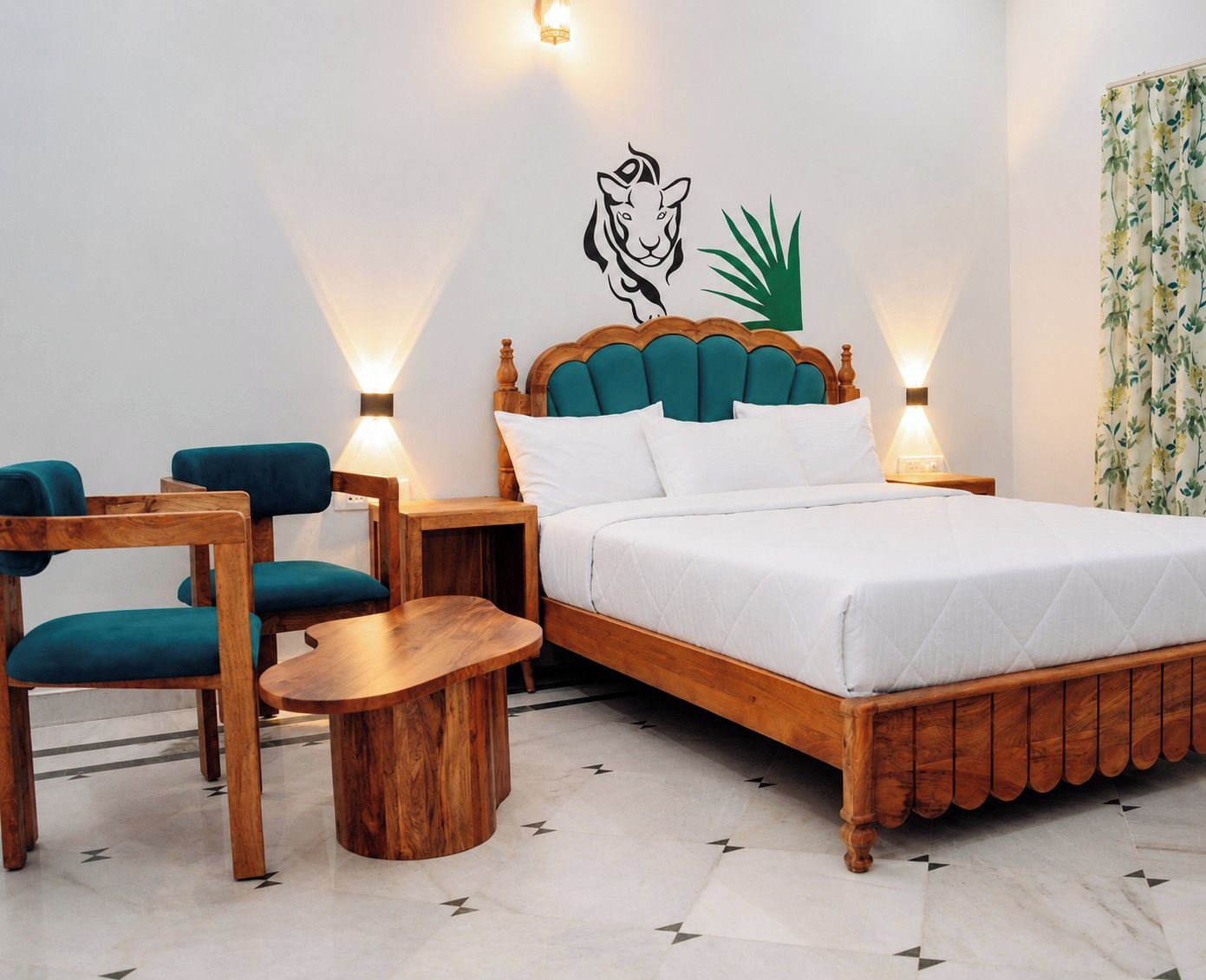 Ein Hotelzimmer mit einem Bett, zwei Stühlen, einem kleinen Tisch und einer Wand mit dekorativen Tier- und Pflanzenmotiven.