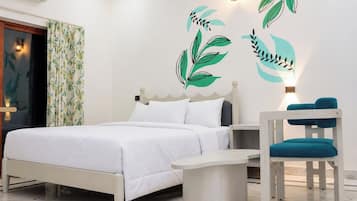 A bedroom with a bed, a bedside table, a chair, and wall art.