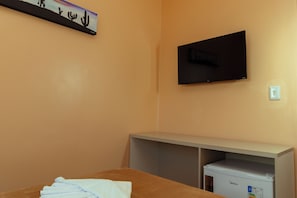 A hotel room with a bed, a television mounted on the wall, and a minibar. - Pousada Trilha dos Cânions (Olho d'Água do Casado)
