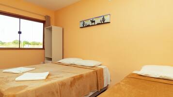 A room with two beds, a window, a painting, and a wardrobe.