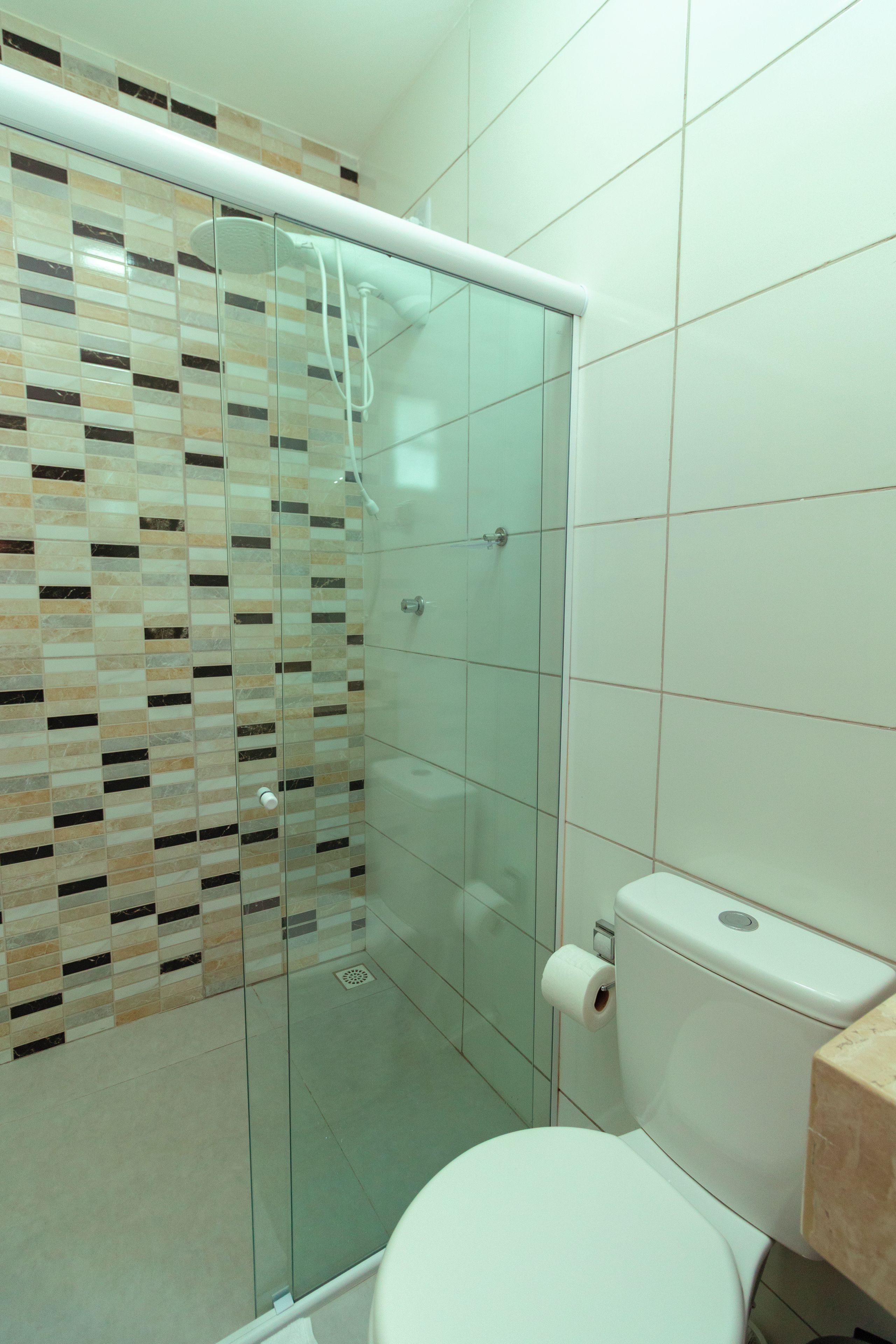 Un bagno con doccia vetrata, un WC e una parete rivestita in piastrelle.