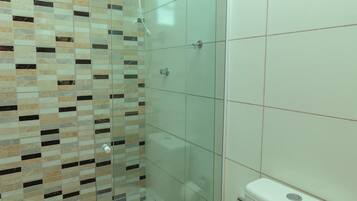 Un bagno con doccia vetrata, un WC e una parete rivestita in piastrelle.