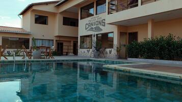 A hotel with a swimming pool, multiple balconies, and a sign reading 'CANYONS'.
