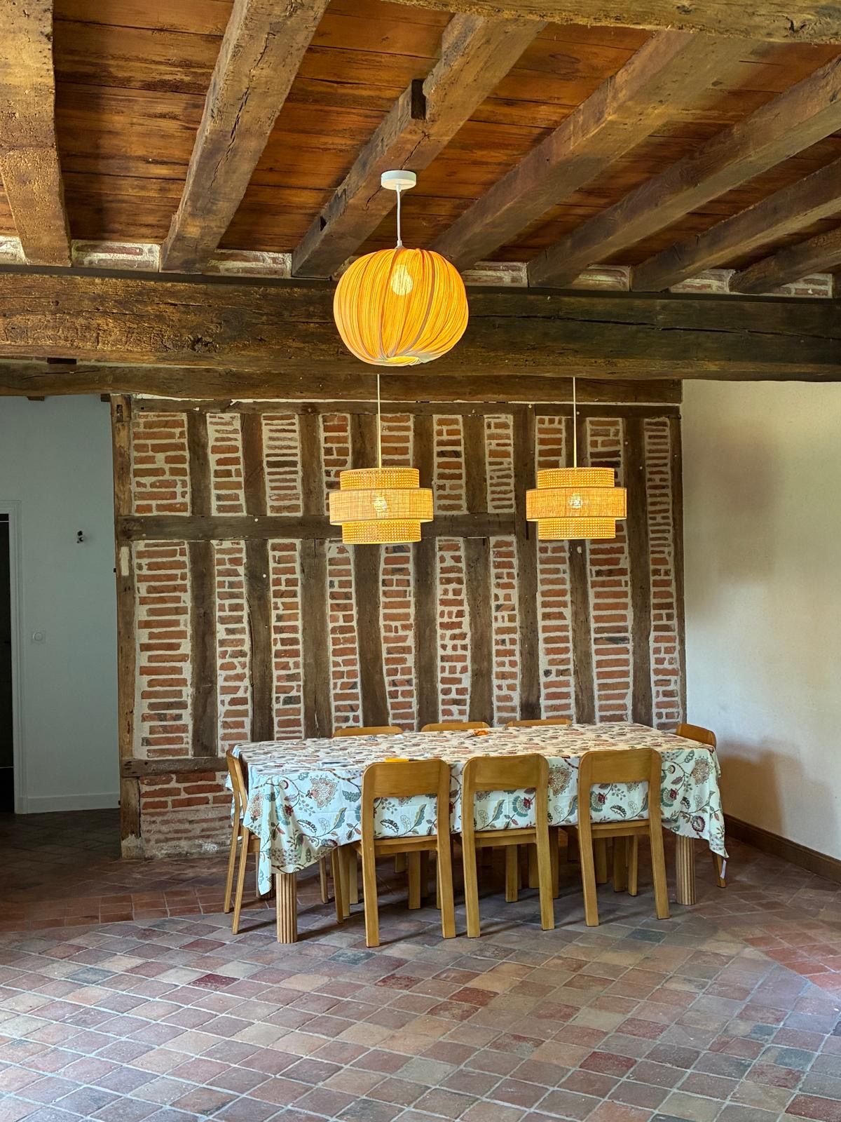 A dining area with a brick wall, wooden beams, and a table set with chairs.
