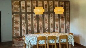 Een eetruimte met een bakstenen muur, houten balken en een tafel met stoelen.
