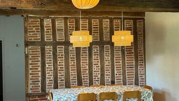 A dining area with a brick wall, wooden beams, and a table set with chairs.