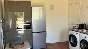 A compact kitchen with a refrigerator, oven, and washing machine.
