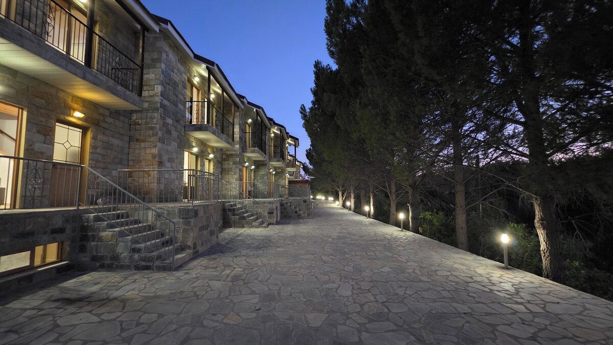 Un edificio de piedra con varios balcones, una escalera de piedra y un camino que lleva a la entrada.