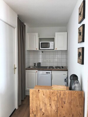 A compact kitchen with white cabinets, a microwave, a dishwasher, and a coffee machine. - Panoramic Mountain View Apt w/ Balcony & Free WiFi (Saint-François-Longchamp)