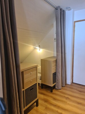 A room with a sloped ceiling, wooden furniture, a door, and a light fixture. - Panoramic Mountain View Apt w/ Balcony & Free WiFi (Saint-François-Longchamp)
