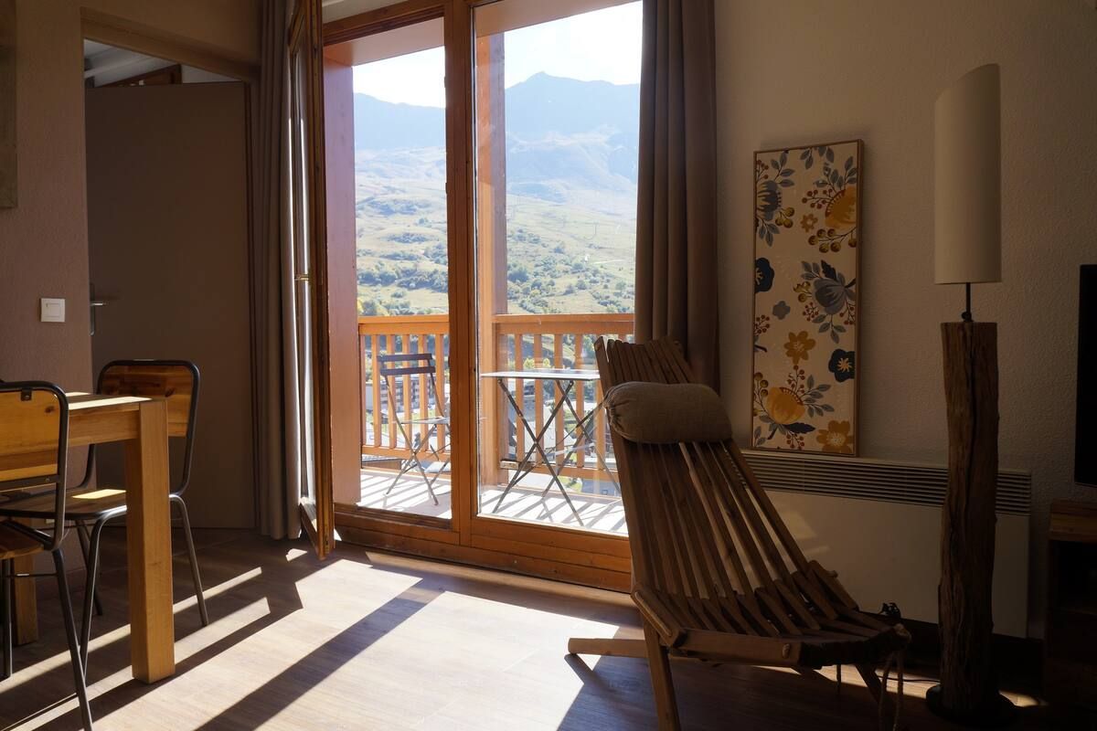 A room with a wooden table and chairs, a cushioned chair, a painting, and a lamp.