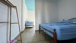 A bedroom with a bed, a wooden ladder, and a metal chair. - Room-sea Pearl Studios Golem - Ground-fl (Golem)