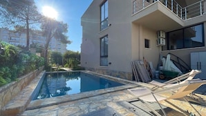 A modern two-story building with a swimming pool, stone flooring, and outdoor furniture. - Room-sea Pearl Studios Golem - Ground-fl (Golem)